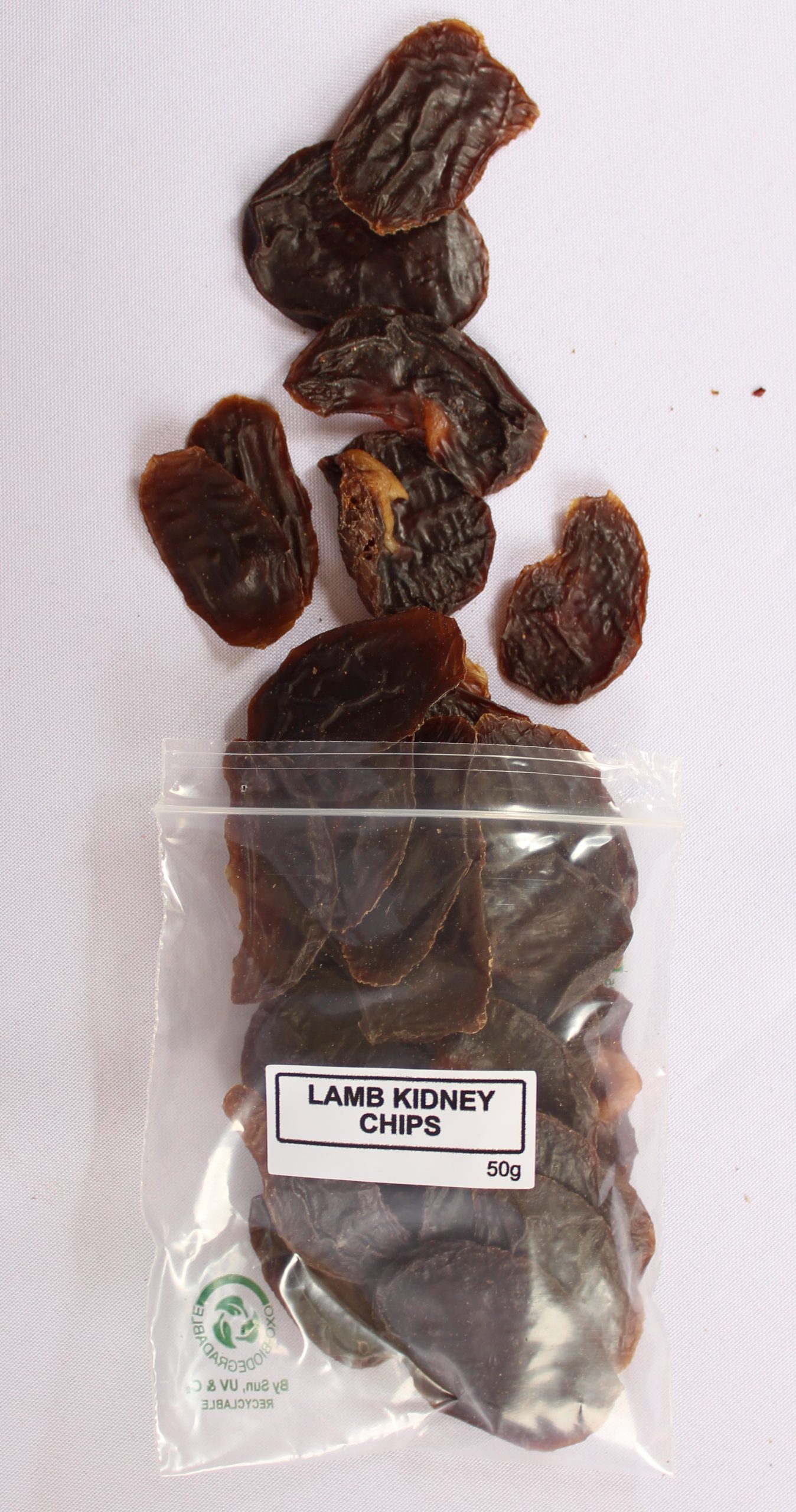 Open bag of air-dried lamb kidney dog treats, with crisp kidney chips spilling onto a surface.